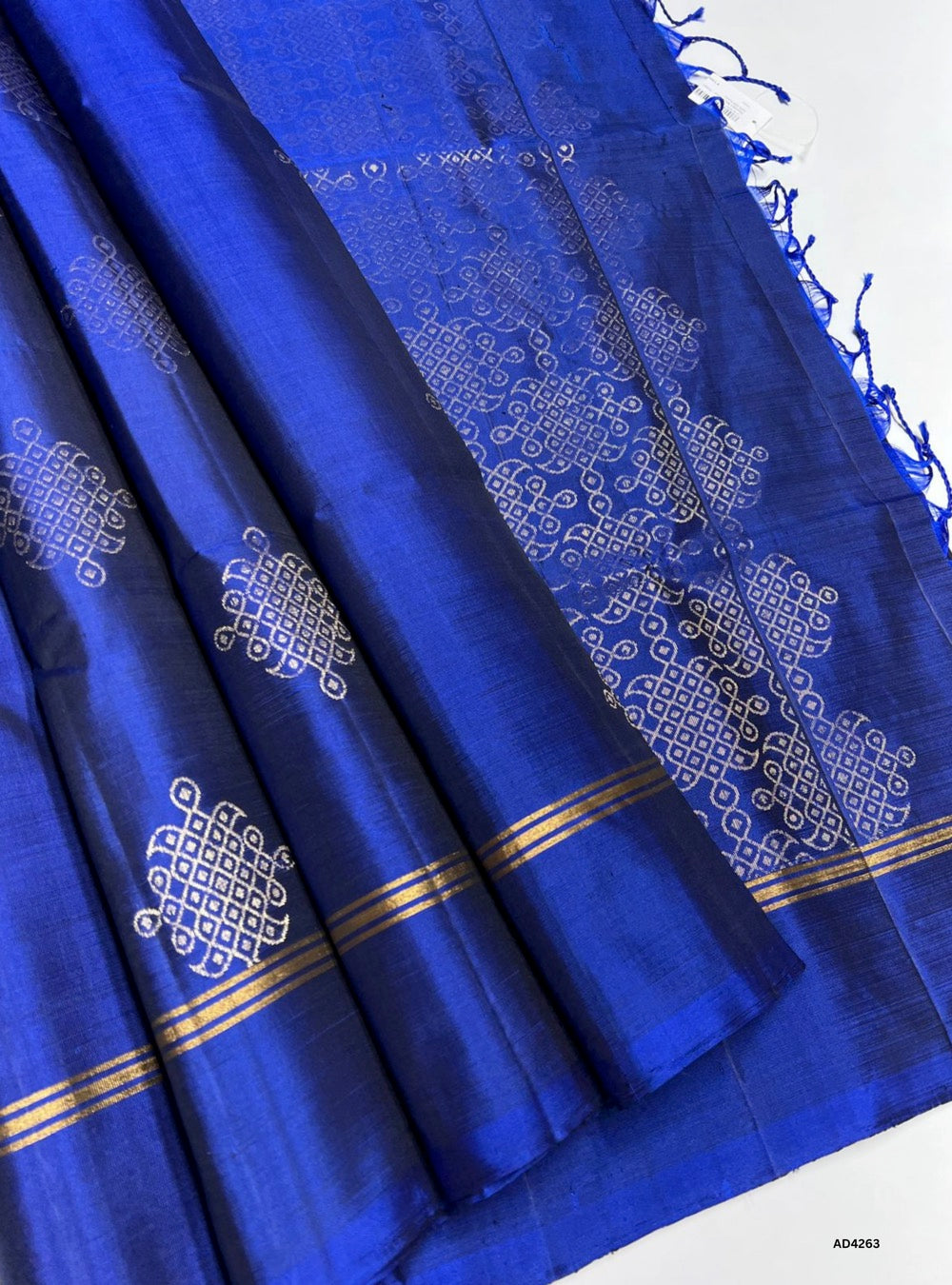 The Royal Blue Kolam Soft Silk Saree is a regal handwoven creation that radiates cultural richness and festive elegance. The majestic royal blue shade symbolizes prosperity, devotion, and timeless grandeur, while the Kolam‑inspired motifs on the border and pallu highlight South Indian artistry. Enhanced with pure gold zari and a lustrous drape, this saree is perfect for weddings, temple ceremonies, and cultural gatherings. It reflects the enduring craftsmanship of Kanchipuram weaving, offering a refined ble
