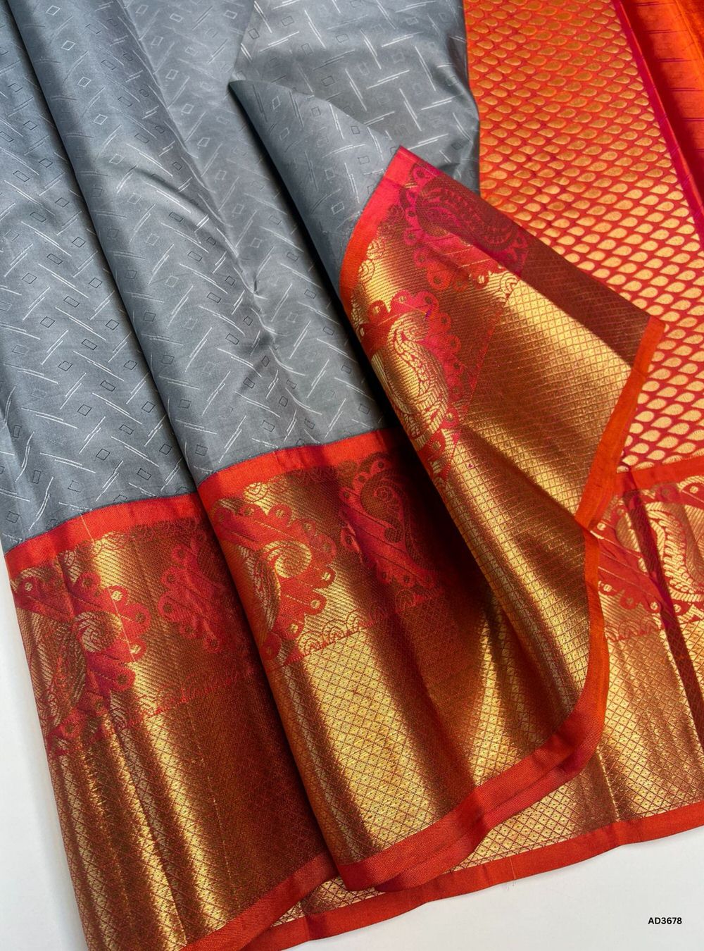 The Silver Grey & Orangish Pink Soft Silk Saree is a graceful handwoven creation featuring a refined silver grey body enriched with shimmering zari. Its festive orangish pink border and pallu showcase the intricate Kanchi style border, adding grandeur and traditional charm. Perfect for weddings, festive occasions, and cultural gatherings, this saree blends subtle elegance with timeless Kanchi craftsmanship.