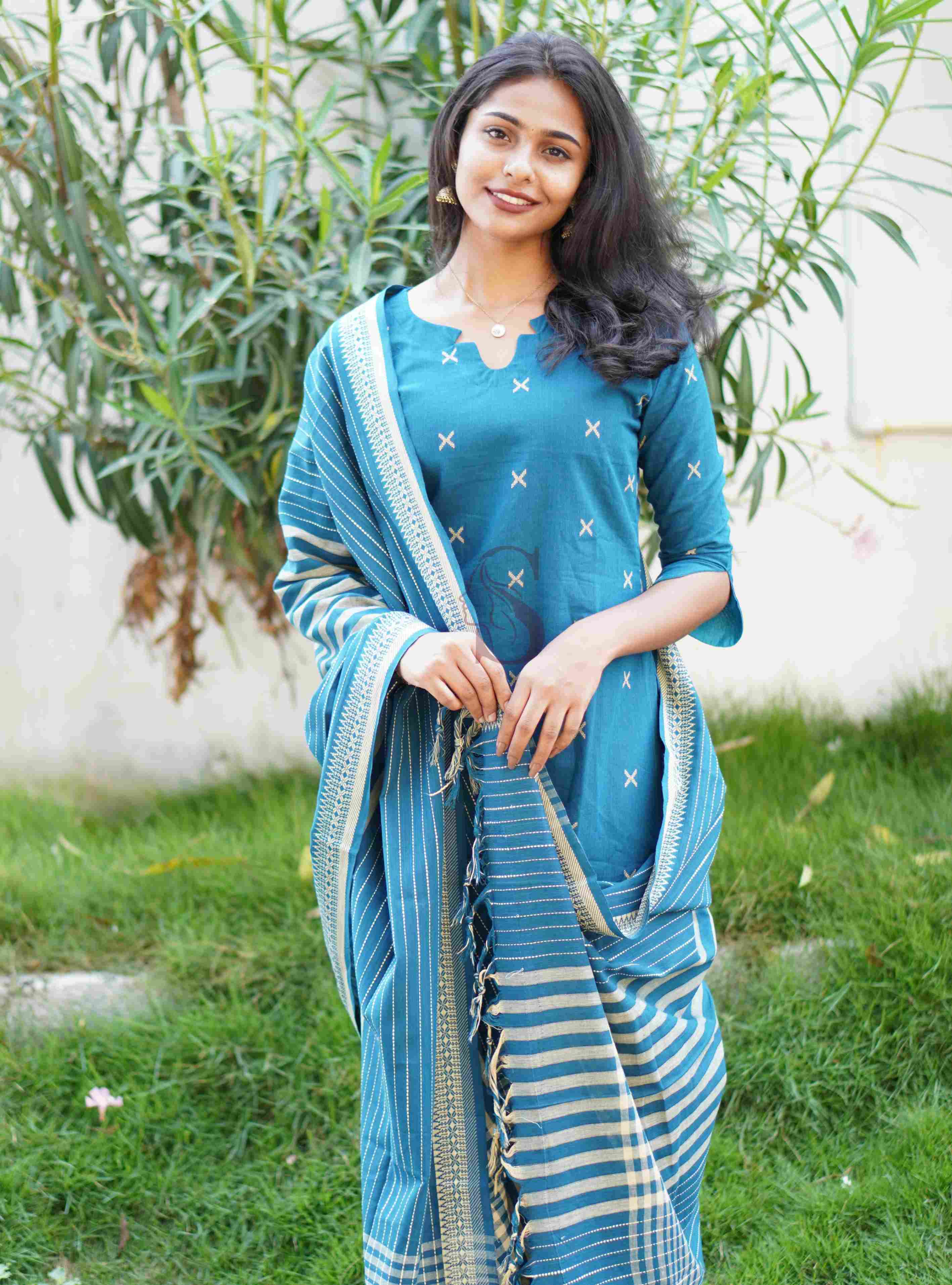 Woman wearing a blue traditional outfit with a matching dupatta in an outdoor setting.